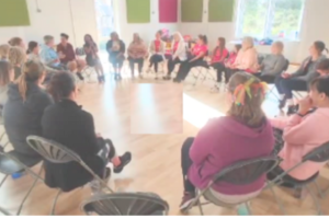 A group of people sitting in a large circle in a bright room